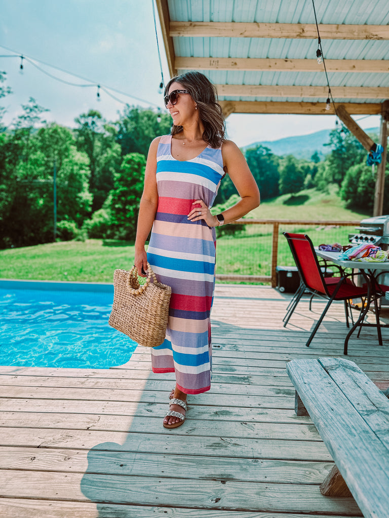 Hannah standing in front of a pool in a long maxi tank dress